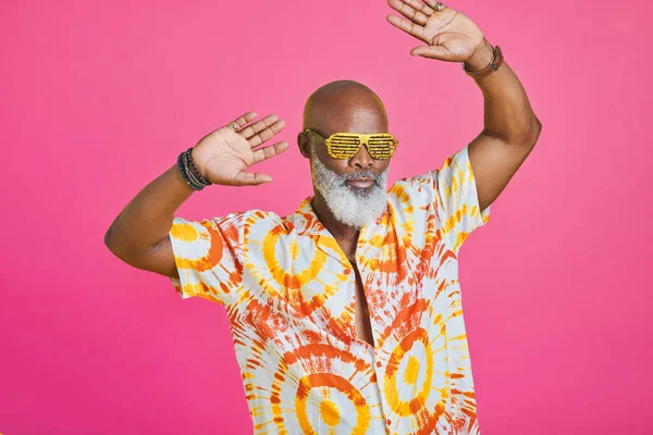 Life is better when youre dancing. a funky and stylish senior man dancing in studio against a pink background