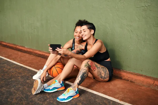 stock image Lets get another selfie. two attractive sportswomen sitting together for a selfie after a basketball game during the day