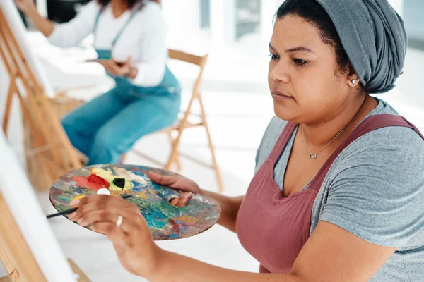 Art is like a form of therapy. an attractive young woman sitting with her friends and painting during an art class in the studio