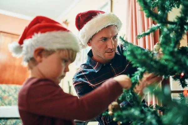 나무를 꾸미는 임무를 맡았지 스러운 아버지와 집에서 크리스마스 트리를 장식하고 — 스톡 사진
