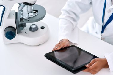 Bilim adamlarına göre dijital tabletler çok kullanışlı. Laboratuvarda çalışırken dijital tablet kullanan tanınmayan bir kadın bilim adamının yüksek açılı görüntüsü.