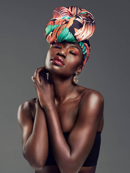 Неоспоримая красота головного убора. Студийный снимок красивой молодой женщины в традиционной африканской головной уборе на сером фоне