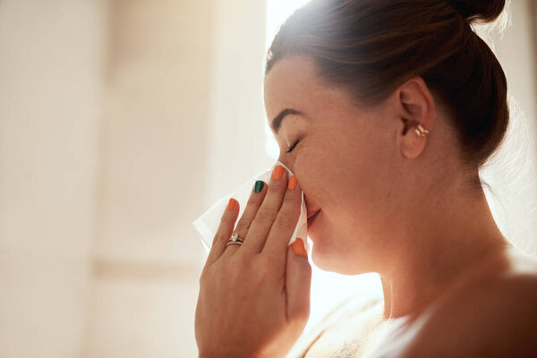 What doesnt belong must go. an attractive young woman blowing her nose during her morning beauty routine at home