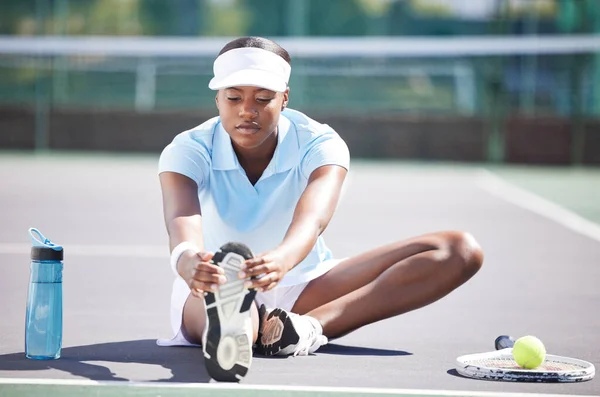 Warm up, tennis and leg stretching by black woman at court for sports, fitness and training on blurred background. Exercise, preparation and foot stretch by athletic girl player on floor before match.