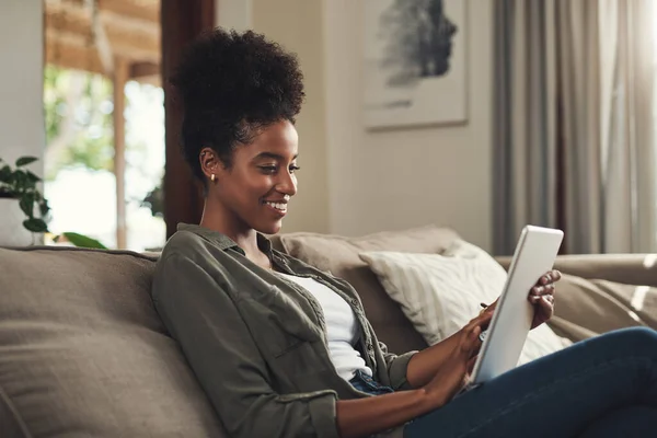 stock image This is definitely my comfort zone. a beautiful young woman using a digital tablet while relaxing on her sofa at home