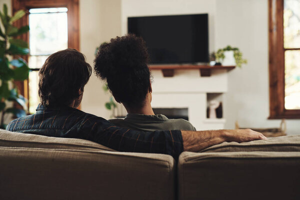 Youre all the company I ever need. Rearview shot of a young couple sitting on sofa and watching tv together at home