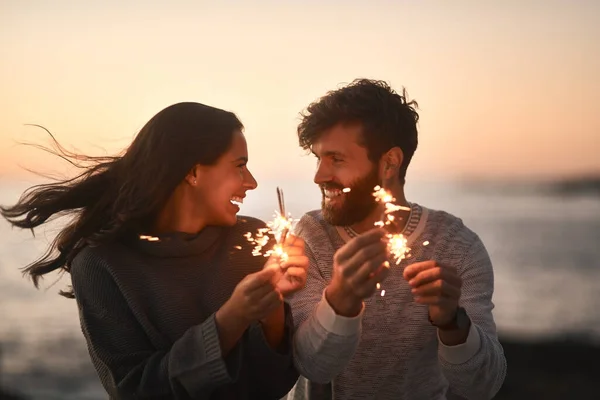 誰が先に燃え尽きるだろう サンセットのビーチでキラキラと楽しそうに過ごす幸せなカップルは — ストック写真