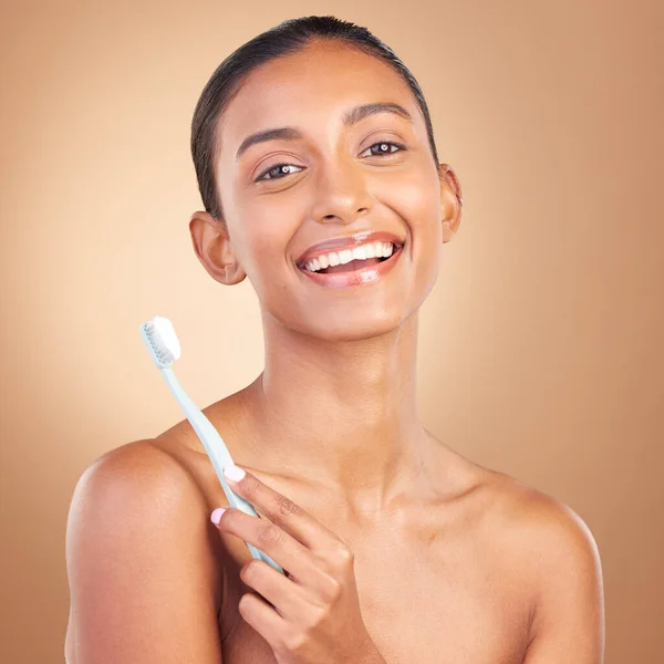 Beauty, smile and toothbrush with portrait of indian woman in studio for brushing teeth, dental and cosmetics. Oral hygiene, clean and self care with model on brown background for routine and health.