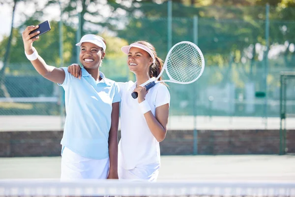 Tennis, friends and selfie at court for training, match or exercise on blurred background. Sports, women and social media influencer smile for photo, profile picture or blog while live streaming.