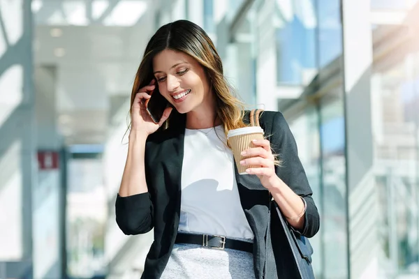 いくつかの重要な電話で彼女の一日を開始 現代のオフィスを歩きながら電話を取る魅力的な若い実業家 — ストック写真