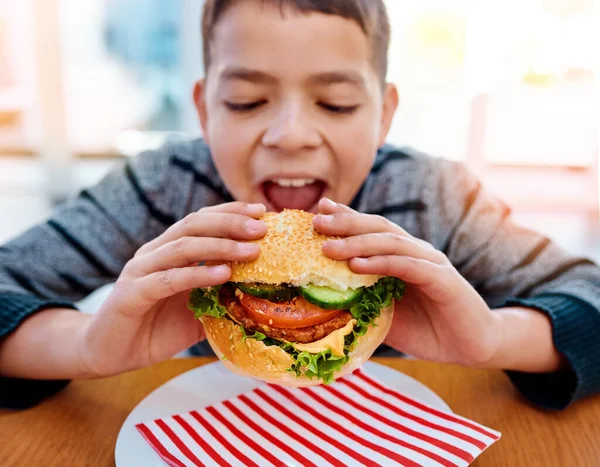 Dar Uma Dentada Enorme Menino Comendo Delicioso Hambúrguer Enquanto Sentado — Fotografia de Stock
