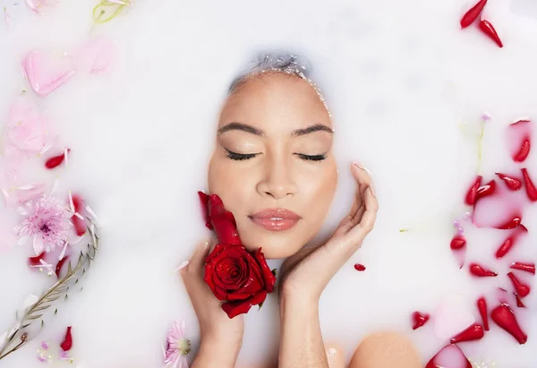 Relax, roses and above of a woman in a bubble bath for luxury, wellness and peace. Content, clean and the face of a beautiful sleeping girl in floral water for relaxing, grooming and stress relief.