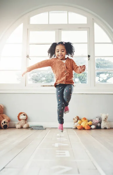 Hopscotch, happy and girl play in home having fun, enjoying games and relax in bedroom. Childhood, kindergarten and excited child balance for jumping game, playing and entertainment activity on floor.