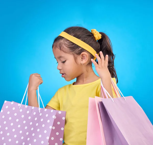 生日聚会 活动或庆祝活动中的女孩 购物袋和礼品袋 以及在工作室里的礼物 商店的选择 袋子和小孩都在看与小孩在一起的蓝色背景的礼物 — 图库照片