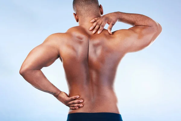 Black man, neck pain and back injury with fitness and health, medical problem and aching body in studio. Emergency, muscle tension and male athlete with joint ache from workout on blue background.