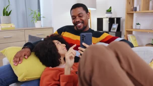 Černý Pár Telefon Relaxovat Pohovce Obývacím Pokoji Komickým Úsměvem Smíchem — Stock video