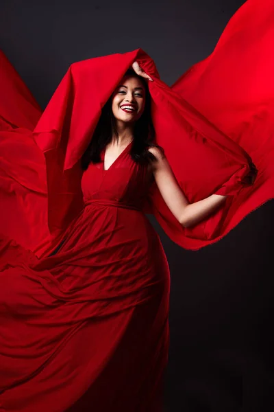 美しさとファッション エネルギーと審美的な動きと暗い背景に赤い芸術 スタジオでの創造的なファブリックデザイナーのドレスで笑顔で絹の動き ファンタジーと芸術モデルを流れる — ストック写真