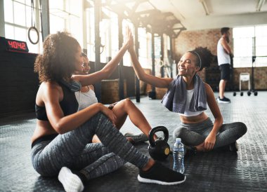 Birlikten kuvvet doğar. Genç kadınlar spor salonunda mola verirken birbirlerine beşlik çakıyorlar.