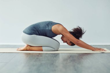 Yoga yoluyla aklın sesine ulaşmak. Çekici bir genç kadının gri bir arka planda yoga yaptığı bir stüdyo fotoğrafı.