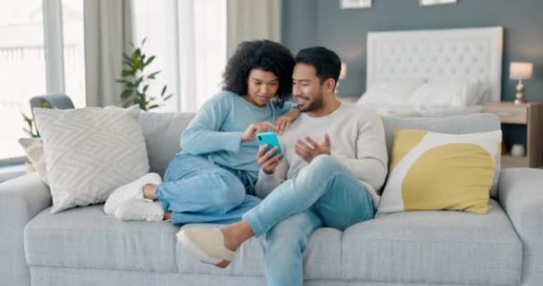 一緒にインターネット上の電話でソファの上のカップル ソーシャルメディアや自宅で映画をストリーミングするためのブラウジング上の多文化的 黒人女性とアジアの男性 スマートフォンを使う若者たち — ストック動画