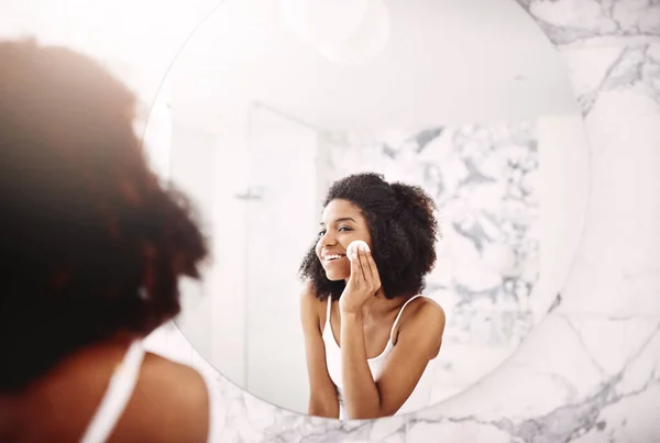 stock image Skin always needs that extra bit of care. an attractive young woman applying moisturizer to her face in the bathroom at home