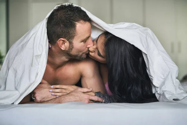 盖在被子下面的亲密时刻一对深情的年轻夫妇躺在被窝里接吻 — 图库照片