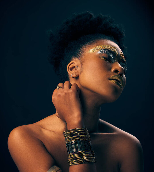 Beauty, gold and jewelry with black woman and makeup in studio for luxury, cosmetics and African pride. Natural, creative and goddess with female model on background for queen, bronze and glamour.