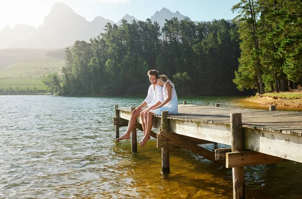 stock image Love, happy and deck with couple at lake for bonding, romance and affectionate date. Nature, travel and holiday with man and woman cuddling on boardwalk in countryside for view, summer and vacation.