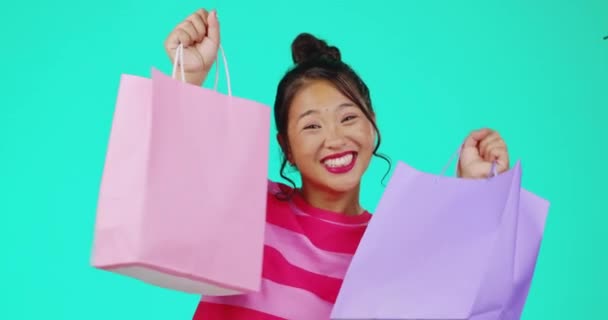 销售和面对一个女人与购物袋隔离蓝色背景在工作室 展示和描绘一个女孩在零售打折 庆祝礼物和礼物后面带微笑 — 图库视频影像