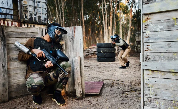 Sports, paintball and man with gun for battle, game or competition outdoors on field. War, military camouflage and male soldier with weapon on shooting range to hide from player in exercise fight