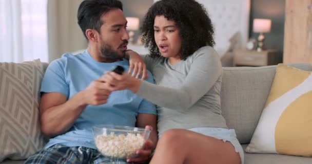 アフリカのカップルはテレビ映画やテレビ映画のためにリモートで戦い リビングルームのソファで一緒にポップコーンを食べます 不満と若い黒人の人々日付ホームラウンジでテレビを見ます — ストック動画