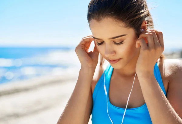 锻炼是我思考人生的时间 一个在海上跑步时听音乐的年轻女子 — 图库照片