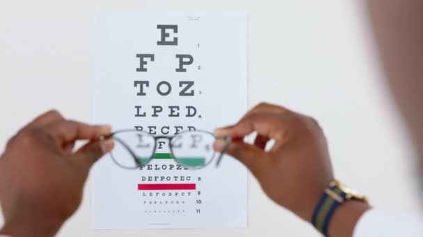 眼鏡やチャートとフォーカス 読書や目のテストのための医師との光学 手紙や医療 テキストと黒の人の手と近視 視力と視力のための眼鏡 — ストック動画