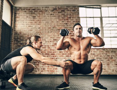 Şimdi bir profesyonel gibi görünüyorsun. İki formda ve kararlı genç adam spor salonunda birbirlerine ağırlık egzersizlerinde yardım ediyorlar.