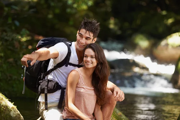 stock image Delighting in natures beauty. a young couple looking at the scenery while hiking through the forest