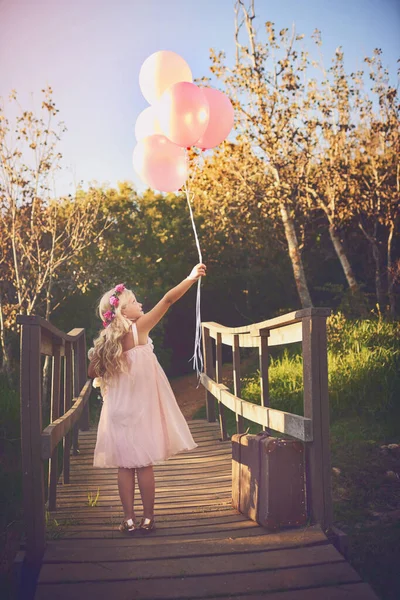 風船が私を幸せにしてくれる 風船とテディベアを持った幸せな女の子が橋の真ん中に立っていて — ストック写真