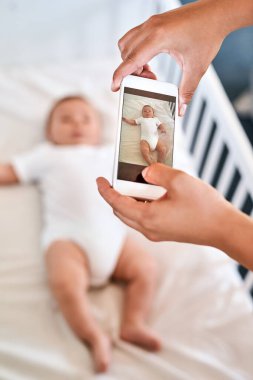 Bebeklerin ilk fotoğraf çekimi. Bir anne cep telefonuyla bebeğinin fotoğrafını çekiyor.