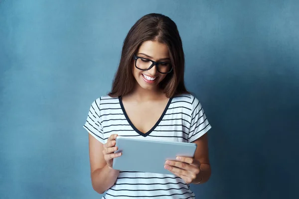 网上有不少有趣的文章 一个年轻貌美的女人用蓝色背景的数码平板电脑拍摄的照片 — 图库照片