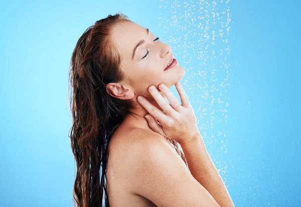 スタジオでのシャワー 水と女性 ウェルネスと審美的な健康のための青の背景とクリーニング スキンケア セルフケアのためのグルーミングのための湿式滴と幸せな女性モデルの洗濯 — ストック写真
