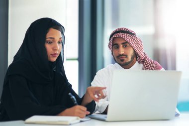Yapılması gereken işler olduğunda ona ulaşıyorlar. Modern bir ofiste dizüstü bilgisayar kullanan iki müslüman iş arkadaşı.