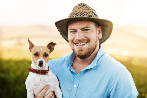 在农场周围有一个朋友是很有帮助的 一个农夫把他的狗抱在葡萄园里的画像 — 图库照片