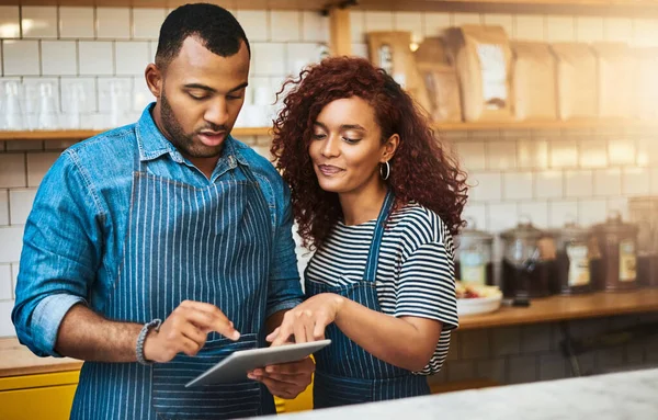 stock image Theyre committed to making their coffee shop a success. an affectionate young couple working on a tablet in their coffee shop