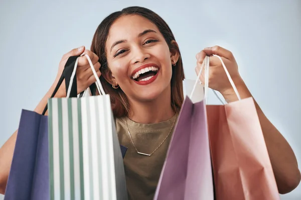 Portrait, happy woman and shopping bag isolated on studio background wealth, financial freedom or sales promotion. Retail, fashion and beauty face of biracial person or customer with paper bags offer.