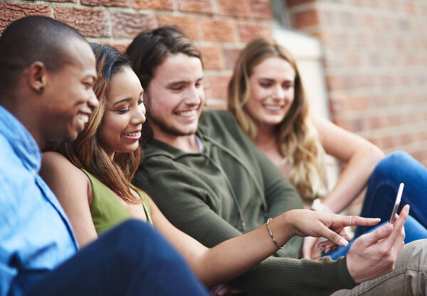 Some things were meant to be shared in real time. a group of young friends using a mobile phone together