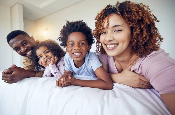 Portrait, selfie and happy family relax in bed, smile and cheerful in the home during morning together. Face, photo and children resting indoors with parents and pose for profile picture and memory.