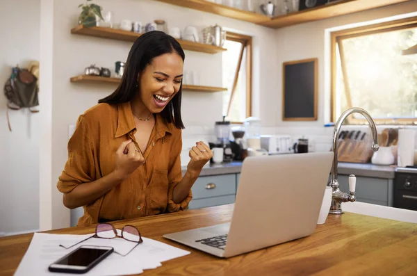 Laptop, success and business woman celebrating finance, savings and investment growth in a kitchen. Online, victory and freelance female excited for good news, loan and startup approval in her home.