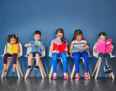 Bilgi büyümenin anahtarıdır. Sandalyeye oturup mavi arka planda kitap okuyan bir grup çocuğun stüdyo fotoğrafları.