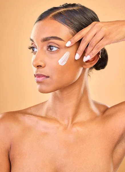 stock image Face, skincare idea and woman with cream in studio isolated on a brown background. Dermatology, cosmetics and thinking Indian female model with lotion, beauty creme or moisturizer for skin health