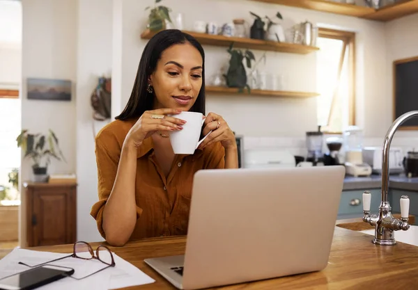 Woman with coffee, remote work and laptop, reading or review with freelance employee drinking hot beverage and content. Working from home, female freelancer and technology with email and connectivity.