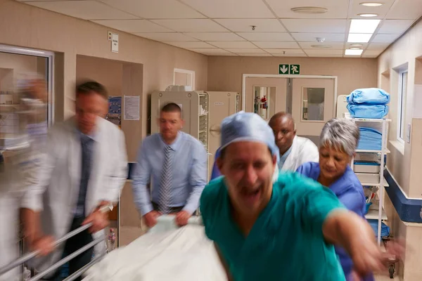 君の緊急事態は我々の専門知識だ 病院の廊下を駆け抜ける医療チームが — ストック写真